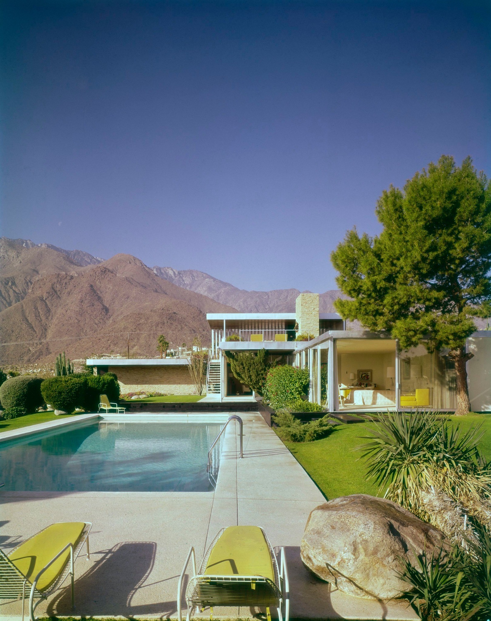Richard Neutra’s Kaufmann House beside its swimming pool, with mountains in the distance.